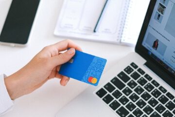 a person holding a debit card infront of a laptop
